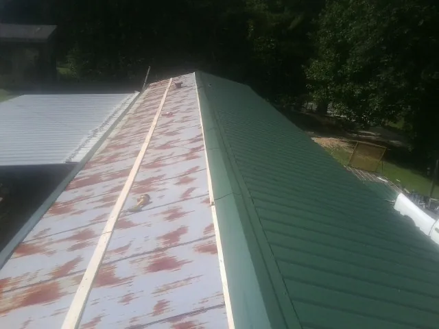 Old rusted panels beside newly installed green metal roofing — Wind Damage Roof Repair by Roofing Brothers in Virden