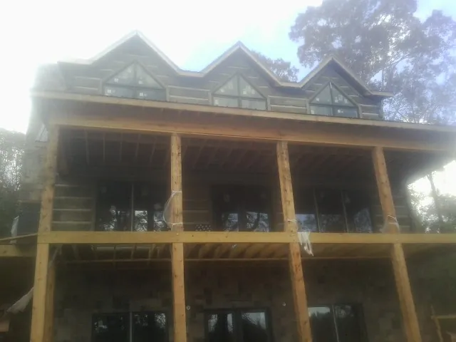 Dormers and porch framing on a large log home under construction — Roof Coating work by our crew in Virden