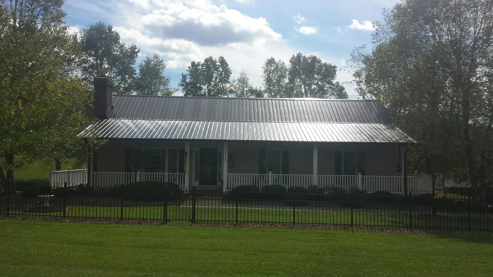 Gray metal roof on a brick ranch with a full width front porch — Gutter Guard Installation work by our crew in Virden