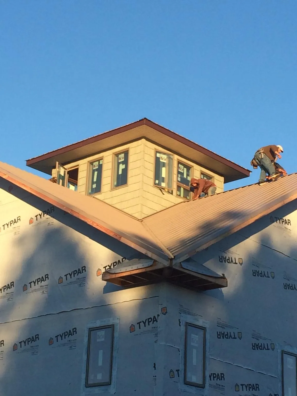 Roofers working around a rooftop cupola on a new metal roof at sunset — Roof Waterproofing in Virden by Roofing Brothers
